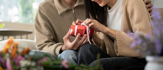 Romantic young asian couple embracing giving present in living room at home. Fall in love. Valentine concept