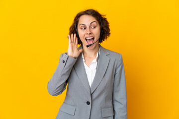 Young English woman isolated on yellow background listening to something by putting hand on the ear