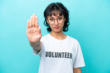Young volunteer Argentinian woman isolated on blue background making stop gesture