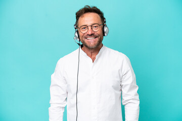 Telemarketer caucasian man working with a headset isolated on blue background with glasses and happy