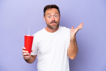 Middle age caucasian man holding soda isolated on purple background having doubts while raising...