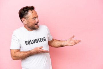 Middle age volunteer man isolated on pink background isolated on pink background with surprise...