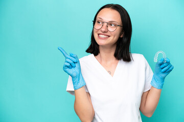Young caucasian woman holding envisaging isolated on blue background intending to realizes the solution while lifting a finger up
