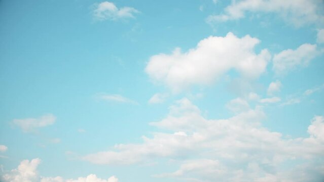 Landscape of pastel colors with white clouds slowly floating across the summer sky.