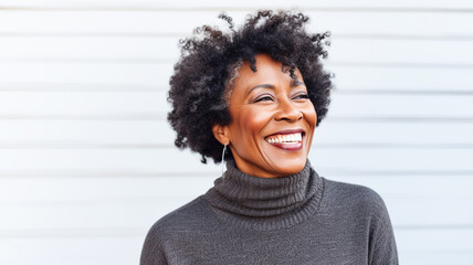 Portrait of middle aged african american woman laughing against white wall, outdoor.

