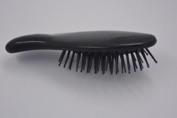Women's accessories and things, black small women's comb with purple inserts placed on white plastic background.