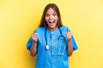 Young nurse caucasian woman isolated on yellow background celebrating a victory in winner position