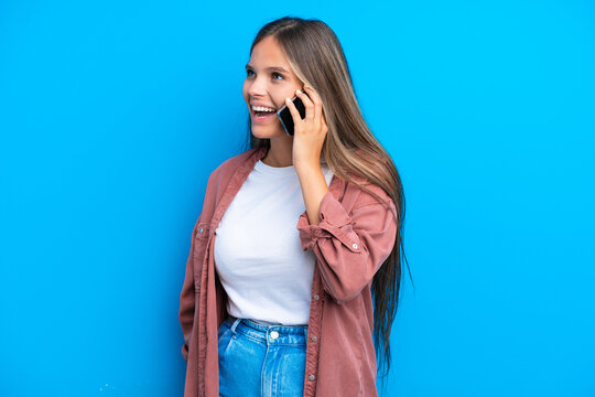 Young caucasian woman isolated on blue background keeping a conversation with the mobile phone
