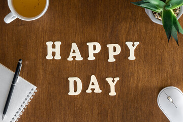 Happy day, wooden letters on the office table, top view.