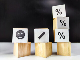 Wooden cubes in a column and a row with white signs with a smiley sign, an arrow, a percentage. The concept of positivism. Positive thinking leads to the achievement of results and profits