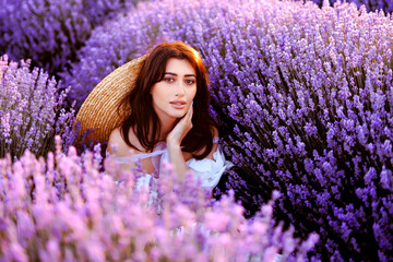  A woman in white dress and straw hat the lavender field on sunset.