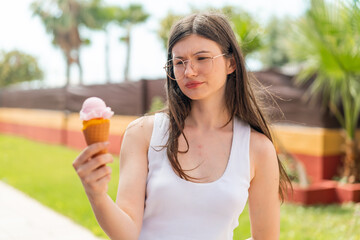 Young pretty Ukrainian woman with a cornet ice cream at outdoors with sad expression