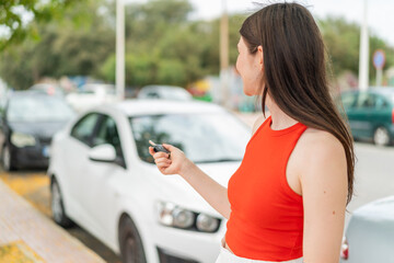 Young pretty woman at outdoors holding car keys