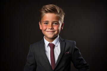 Portrait of a cute boy in a suit on a dark background.