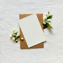 Blank greeting card, invitation and envelope mockup. Minimal floral frame made of jasmine flower branch. Flat lay, top view. Happy mother's day, women's day or birthday, wedding composition.