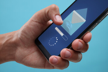 Got new message. Man using smartphone on light blue background, closeup
