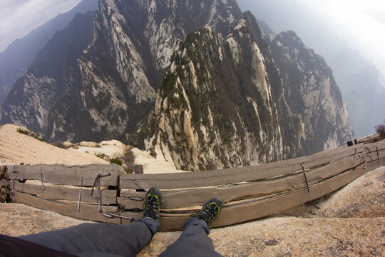 Hua Shan mountains in China. High cliff plank walk. Hiking up the mountain. Abyss trail. Dangerous climbing. Famous walk at the edge. Wooden path over abyss. Xian city in China.
