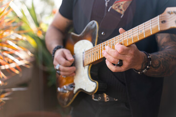 Hipster guitarist playing an electric guitar outdoors.