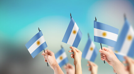 A group of people are holding small flags of Argentina in their hands.