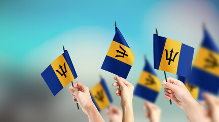 A group of people are holding small flags of Barbados in their hands.