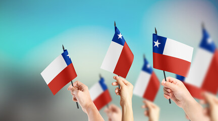 A group of people are holding small flags of Chile in their hands.