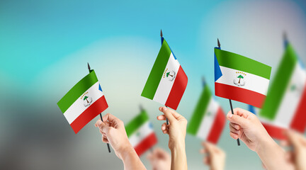 A group of people are holding small flags of Equatorial Guinea in their hands.
