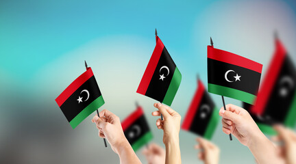 A group of people are holding small flags of Libya in their hands.