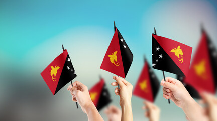 A group of people are holding small flags of Papua New Guinea in their hands.