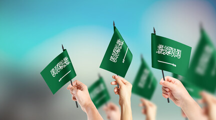 A group of people are holding small flags of Saudi Arabia in their hands.