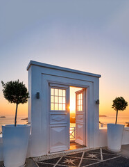 Beautiful sunset seen through an open white door overlooking the sea and Caldera, Santorini,...
