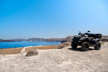 Quad bike parked on the seafront of the Akrotiri peninsula in the southwestern part of the island of Santorini with a view of the caldera. Travel, relaxation, adventure.