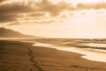 Awesome footprint and sun light beautiful  nature landscape on the coastline and sandy beach with mountains in background and clouds and horizon - summer oudor wild concept and explore lifestyle