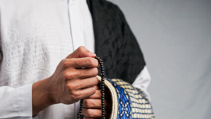 man is praying with prayer beads and carrying a prayer mat