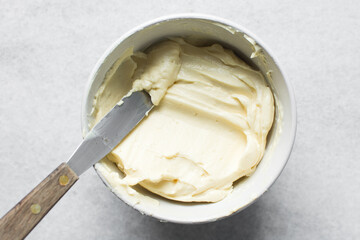 Top view of cream buttercream in a white mixing bowl, silky smooth american buttercream in a ceramic bowl, overhead view of smooth buttercream