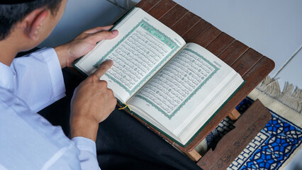 Fototapeta na wymiar close up photo of a Muslim man reading the Quran on a prayer mat during the holy month of Ramadan.