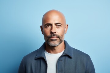 Portrait of mature man with beard looking at camera against blue background