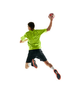 Full-length image of young handball athlete in motion during game, throwing ball against white studio background. Motivation to win. Concept of professional sport, tournament, competition