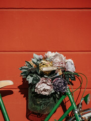 Green bicycle with decorative basket near terracotta wall