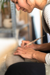 Fototapeta premium Intimate view of a potter deeply focused on shaping a piece of clay on a pottery wheel, capturing the essence of ceramic artistry.