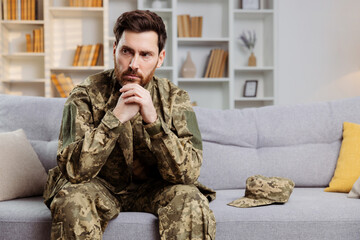 Soldier returning home theme. Distressed man in Ukrainian army gear seated by himself on a couch