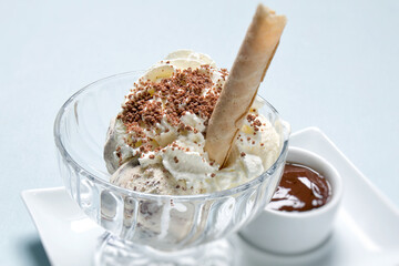 Coupe gevuld met bolletjes ijs, slagroom en nootjes. Daarnaast staat op het witte bord een chocoladesaus. Dame blanche is een populair frans nagerecht.