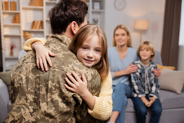 Soldier in uniform surprises family, who look on in delighted shock, cherishing unexpected reunion
