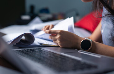 Close-up of a busy professional sorting through extensive paperwork with a smartwatch visible..