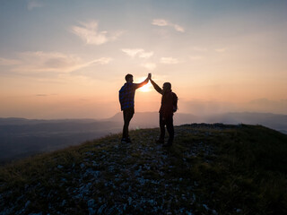 Teenage hiking adventure, a cheerful teen girl and a teen boy giving high five on the mountain top,...