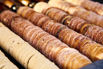 Process of baking trdelnik in Prague, Grilled rolled dough topped with sugar, Traditional Czech hot sweet pastry, street bakery in Prague