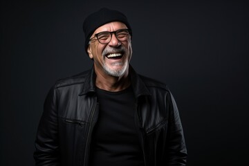 Portrait of a happy senior man laughing while wearing a black leather jacket and hat.