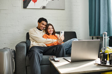 A couple captures a moment of love and technology as they smile for a selfie in hostel living room