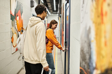 Young multicultural couple smiling in hostel hallway, happy woman opening door to their room