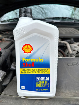 NORWALK, CT, USA - FEBRUARY 11, 2024: Bottle with Shell motor oil SAE 10W 40    on car with open hood