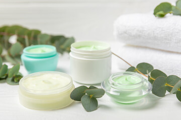 Fototapeta na wymiar Jar of moisturizing cosmetic cream for face, hands and body with eucalyptus leaves on a white wooden background. Natural organic product. Beauty and spa concept. Body care. Space for text.Copy space.